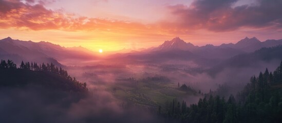 Fototapeta premium Foggy sunrise over majestic mountains casting a serene glow amidst the misty landscape and dense forest silhouettes.
