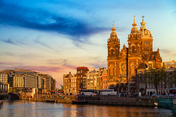 Fototapeta premium Canal and St Nicholas Church in Amsterdam at colorful sunset ,Netherlands. Famous Amsterdam landmark near Central Station.