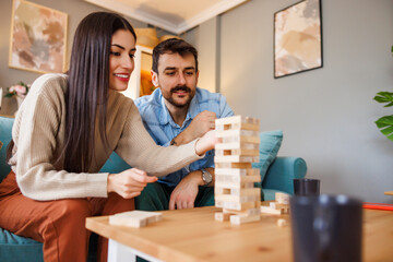Husband and wife having fun playing wooden block stacking balance game
