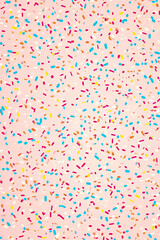 Colorful confetti scattered on a pink background, featuring an array of vibrant dots, creating a lively and playful atmosphere, ideal for celebrating events and parties.