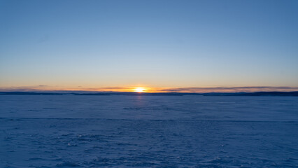Frozen Horizon Under Winter Dawn - The sun rises over the frozen expanse of Khovsgol lake, casting a soft golden hue across the icy landscape.