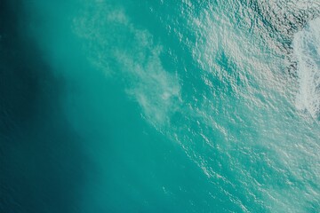 Obraz premium Aerial View of Turquoise Ocean Waves with White Foam and Sunlit Water Surface Patterns