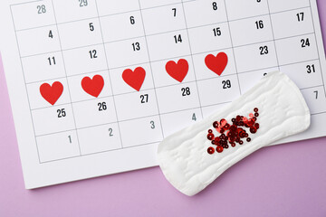 Calendar with marked dates and menstrual pad with sequins on lilac background, top view