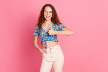 Smiling young woman giving thumbs up on pink background
