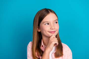 Portrait of a cheerful preteen girl posing against a vibrant blue background, conveying happiness...
