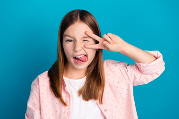 Fototapeta premium Playful girl making a funny face with a blue background while posing cheerfully