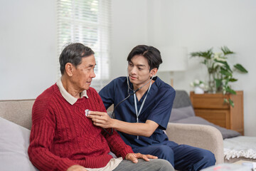 Nurse using stethoscope to check elderly patient's heart in home setting.