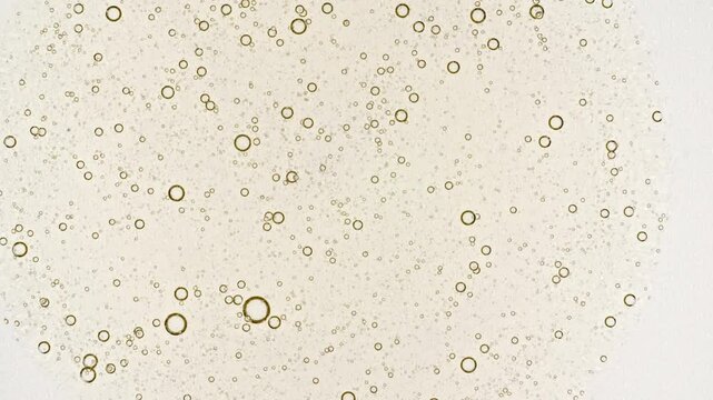 Transparent cosmetic yellow gel fluid with molecule bubbles oil spreading on a white background. Macro Shot of Natural Organic Cosmetics, Medicine. Production Close-up. Slow Motion. 4k