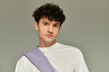 Obraz premium Fashionable young man showcasing trendy style in a minimalist setting