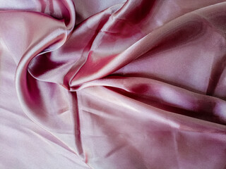 Pink silk fabric for background.The wrinkled light pink fabric lies in folds and drapery. Textile texture in pink color