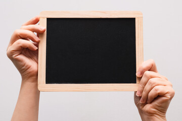 Woman's hand showing chalkboard. Place for writing text on a blackboard. Hands holding a empty black board on white