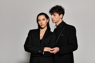 Stylish young couple poses elegantly in trendy black outfits against a minimalist backdrop