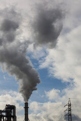 Chimney with smoke from a wood processing industry and an electric power pole. Electricity with blue sky and white clouds. Pollution