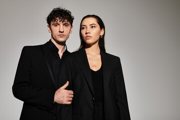 Stylish young couple exuding confidence in chic black attire against a minimalist backdrop