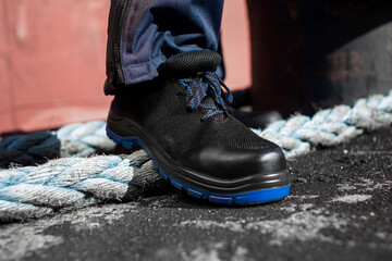 A person is wearing a pair of black shoes with blue laces