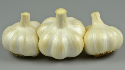 Obraz premium Three Fresh Garlic Bulbs on a Gray Background for Culinary Use