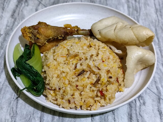 Fried rice, vegetables, crackers and fried chicken. Fried rice on a plastic plate.