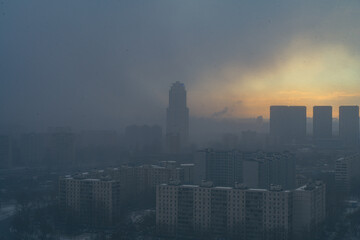 Fototapeta premium A snowstorm covers the big city, a gloomy sky with glimpses of the sun. Aerial shooting. Space for text.