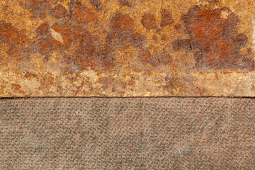 Close up of a weathered book cover - two pieces of brown surface, the top piece is faded with light brown stains and a rough rusty texture, and the bottom piece has a fine textile grain