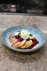 Pancakes with ice cream and berries on rustic background.