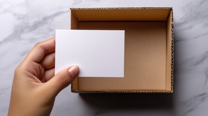 Hand holding blank card above empty box.