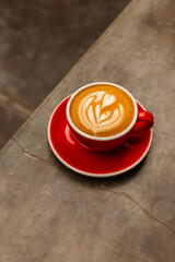 Cappuccino coffee in red cup on concrete table Delicious flat white with latte art on a gray background