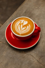 Cappuccino coffee in red cup on concrete table Delicious flat white with latte art on a gray background