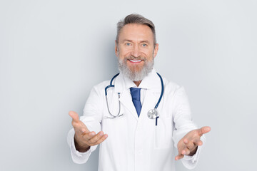 Smiling senior doctor in white coat holding arms open welcoming patients in hospital