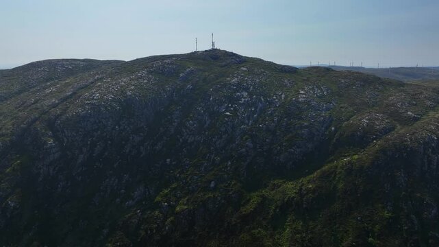 Barnesmore Gap, County Donegal, Ireland, June 2023. Drone tracks left across a dense green forest hillside with speckled exposed rock and a telecommunications tower on top of the mountain.