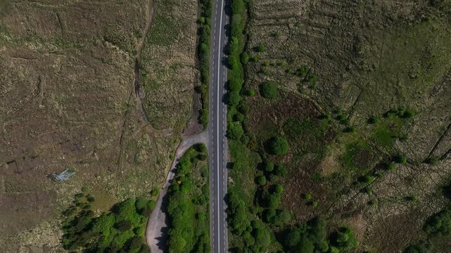 Barnesmore Gap, County Donegal, Ireland, June 2023. Drone in Bird&rsquo;s Eye View pulls backwards above the road as cars navigate the route through forested boglands with meandering steams on a sunny day.