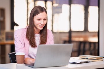 Female employee working in office with bokeh lights, working overtime according to project deadline using laptop technology. financial graph document