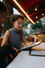 Woman ordering food using digital menu at restaurant with friend