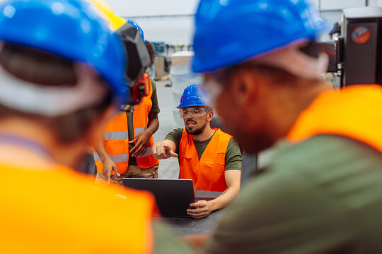 Engineers using laptop discussing project in factory