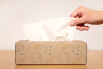 Close-up of a hand taking a tissue from a box.