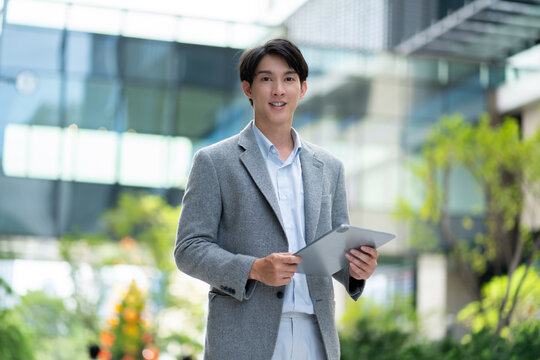 Portrait Businessman Working on tablet Computer and smile at modern Office Building.investment,real estate,finance, technology,internet,investment,stock market and global business concept - Powered by Adobe