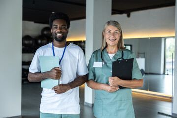 Mid aged female doctor standing with a dark-skinned intern in the clinic hall