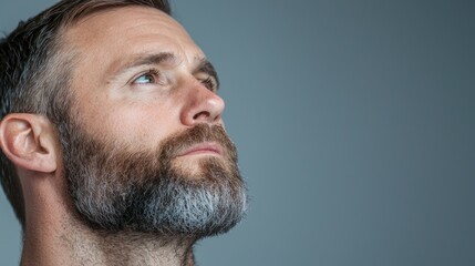 Obraz premium Man looking up, pensive expression, grey background, profile portrait, website use