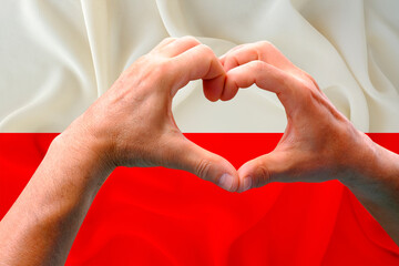 close-up of male hands in heart form against background of silk national flag of European state of...