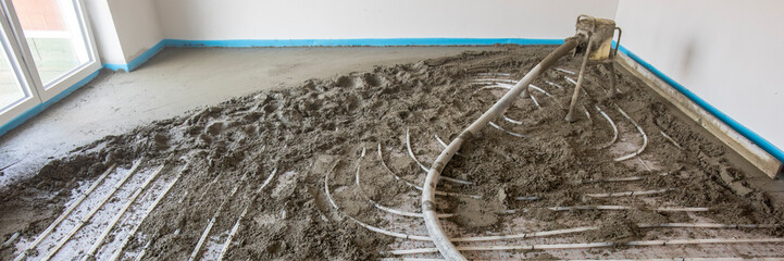 In einer Neubauwohnung wird auf den Heizschlangen einer Fußbodenheizung der Estrich verlegt.