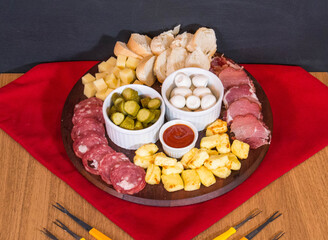 Top view of appetizers table with charcuterie, snacks, bread, cucumber, quail eggs, ketchup and cheese. Food board with cutlery next to it.