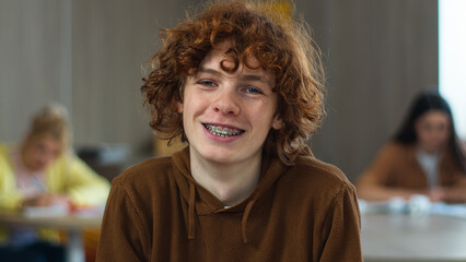 Caucasian happy student teen teenager pupil male boy guy man studying learning at school class university college lesson study learn smiling toothy braces tooth dental medicine smile looking at camera