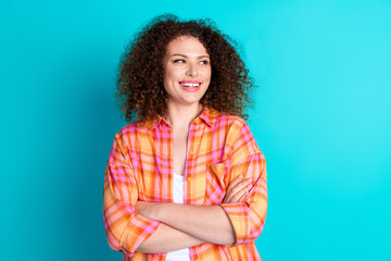 Fototapeta premium Smiling young woman in checkered shirt with arms crossed against a bright turquoise background