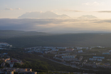 Beautiful morning cityscape. Top view of the buildings and streets of the city. Residential urban areas at sunrise. Volcanoes in the distance. Petropavlovsk-Kamchatsky, Kamchatka, Far East of Russia.