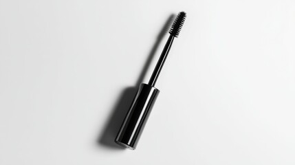 Black mascara tube with a silver cap, lying flat on a clean white background with soft shadows.