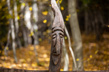 a head carved in wood by an unknown artist against the background of a forest in autumn colors