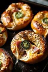 freshly baked soft pretzels filled with melted cheese, ham, and jalapeños, topped with poppy seeds, arranged on a rustic dark baking sheet, one pretzel torn open revealing gooey, stretchy cheese 