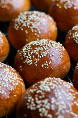 A close up of a number of round homemade burger buns resting on a cooling tray