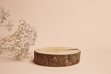 Natural wooden pedestal podium with bark edges, accompanied by delicate dried flowers on a neutral beige background. Ideal for product display, branding, or organic decor