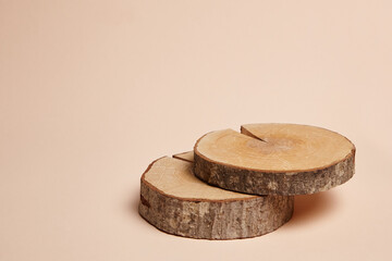 Two rustic wooden pedestals stacked on a neutral beige background. The natural bark texture and circular wood grain add an organic and minimalist aesthetic