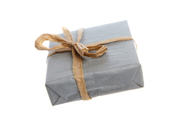Small rectangular gift box wrapped in gray paper and secured with a rustic twine bow. Minimalist...